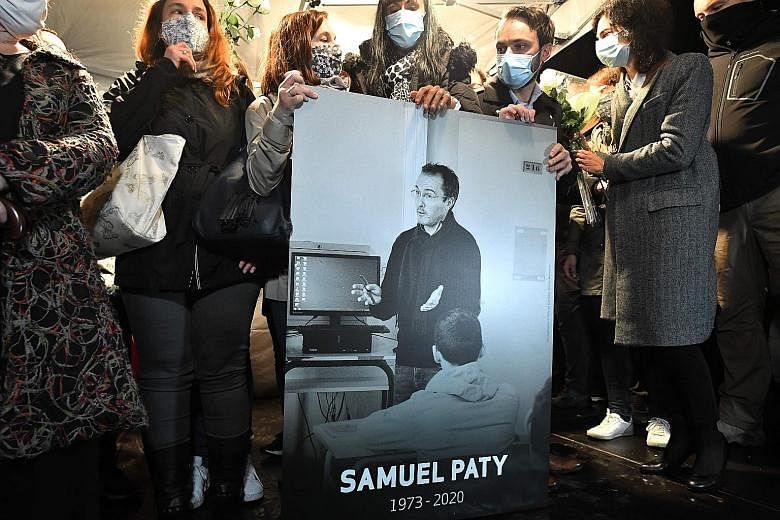 Relatives and colleagues holding a picture of history teacher Samuel Paty during a march to honour him in Conflans-Sainte-Honorine, the suburb outside Paris where he taught, on Tuesday. Mr Paty was beheaded for showing students cartoons of Prophet Mu