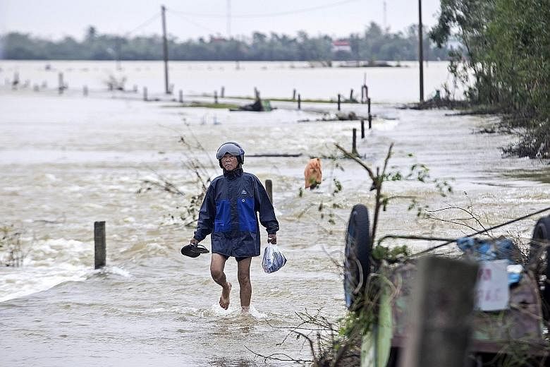 A man walking through floodwater in Thua Thien Hue province, Vietnam, on Tuesday. Twenty people are missing in central Vietnam following weeks of severe flooding and landslides, the authorities said yesterday, as the country braced itself for yet ano