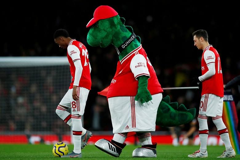 Mesut Ozil (right) and Arsenal club mascot Gunnersaurus are two figures who will not be involved in a match for the considerable future. Ozil has been left out of the club's Premier League and Europa League squads, while the dinosaur mascot was axed 