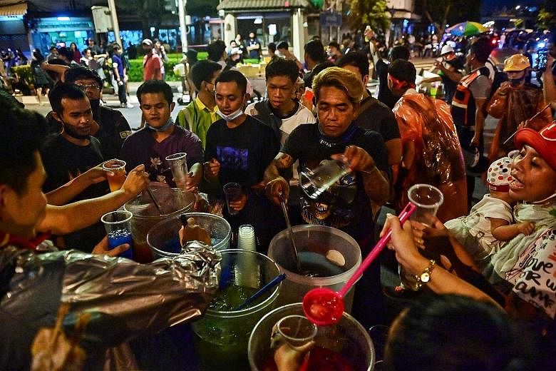 Pro-democracy protesters getting drinks from a street food vendor during an anti-government rally in Bangkok on Wednesday. PHOTO: AGENCE FRANCE-PRESSE