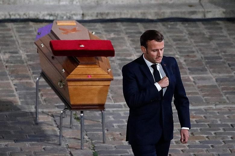 Top: Mourners gathering at the Place de la Sorbonne in Paris on Wednesday to watch a national homage to Mr Samuel Paty. Above: President Emmanuel Macron paying his respects by Mr Paty's coffin inside Sorbonne University's courtyard in Paris on the sa