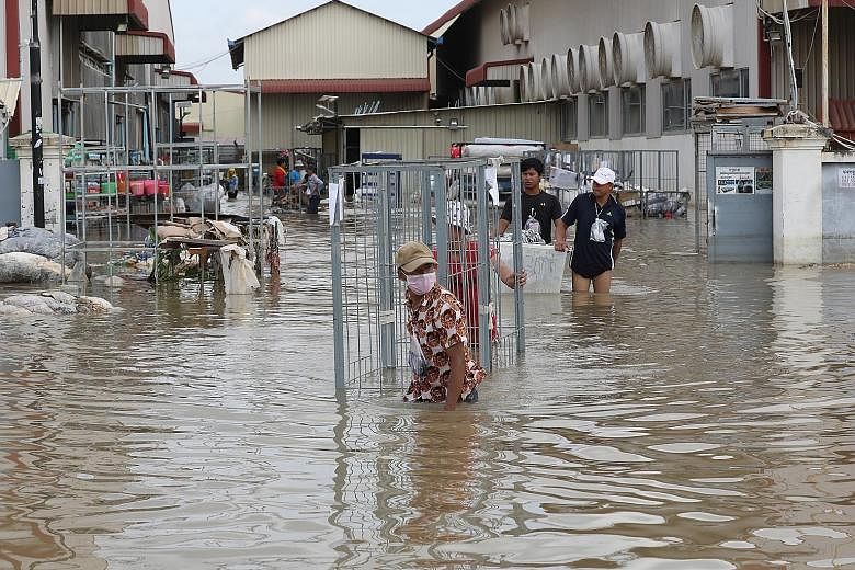 Garment workers gathering clothes from a flooded factory on the outskirts of Phnom Penh, Cambodia, yesterday. Cambodia, Vietnam and Laos have experienced heavy rainfall since the start of this month, which has been exacerbated by the arrival of tropi