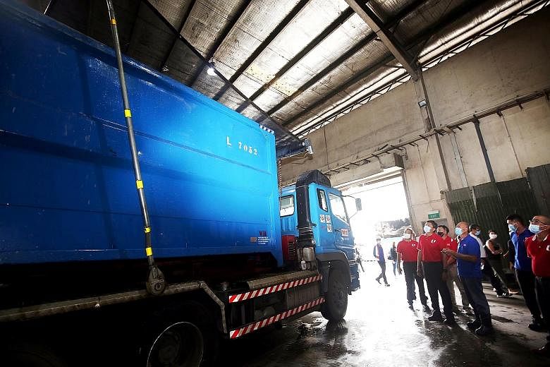 NTUC secretary-general Ng Chee Meng (second from left) and other union representatives observing a garbage truck, which is fitted with a device to unfurl a net to prevent trash from flying out in transit, during their visit to waste management firm W