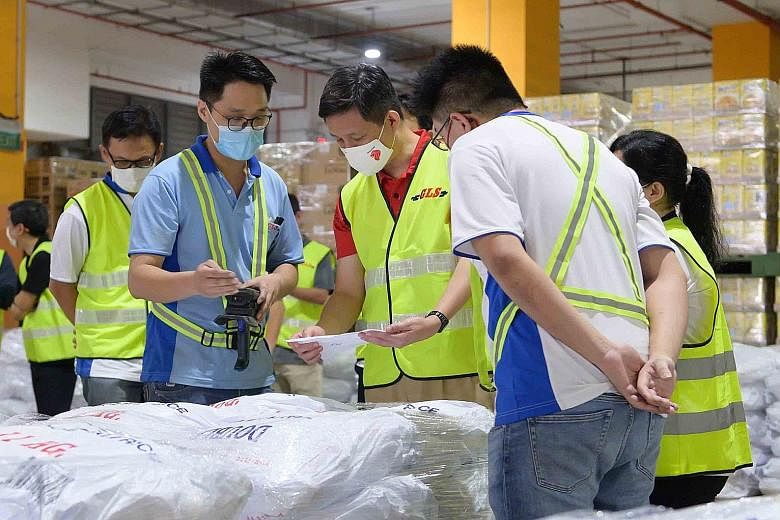 Minister for Trade and Industry Chan Chun Sing with staff during a visit to FairPrice's Benoi Distribution Centre in Joo Koon yesterday. 	Mr Chan, who also paid a visit to a cold storage facility for frozen meat, said in a Facebook post that staff at