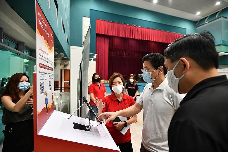 Education Minister Lawrence Wong talking to Ms Ong Shu Pei (in red), e2i's assistant director of hospitality and wellness, during a visit to the North West SkillsFuture Marketplace at Yew Tee Community Club yesterday. ST PHOTO: LIM YAOHUI