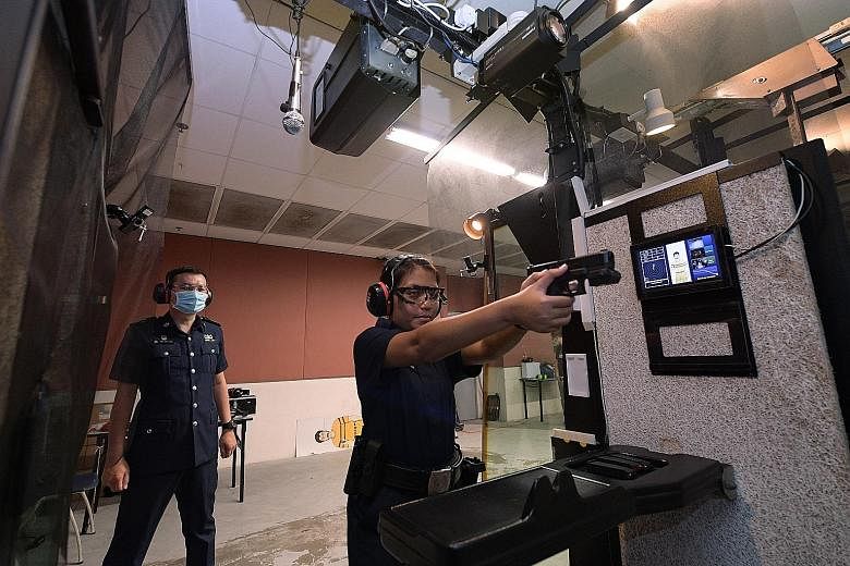 Senior Staff Sergeant Ang Eng Hau (left) observing trainee Noorafidah Mohamed Nasar during a demonstration of the Enhanced Live Firing Range System at the Home Team Academy last Wednesday.