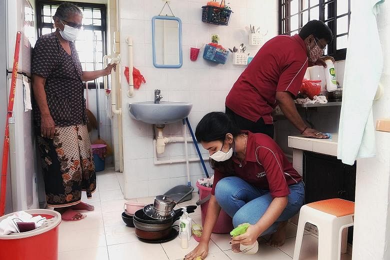 Madam Govindamal Mariappan, 89, watching volunteers clean her home in Bukit Merah yesterday. More than 50 of them from the Singapore Indian Development Association and Young Sikh Association took part in a new initiative, known as Project Shine, to h