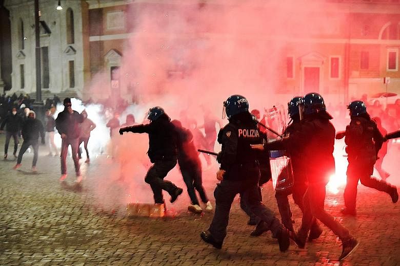 Italian police officers (above) clashing with far right Forza Nuova party activists in Rome's Piazza del Popolo during a protest last Saturday against the government's measures to curb the spread of Covid-19. Workers (below) piling up chairs at a bar