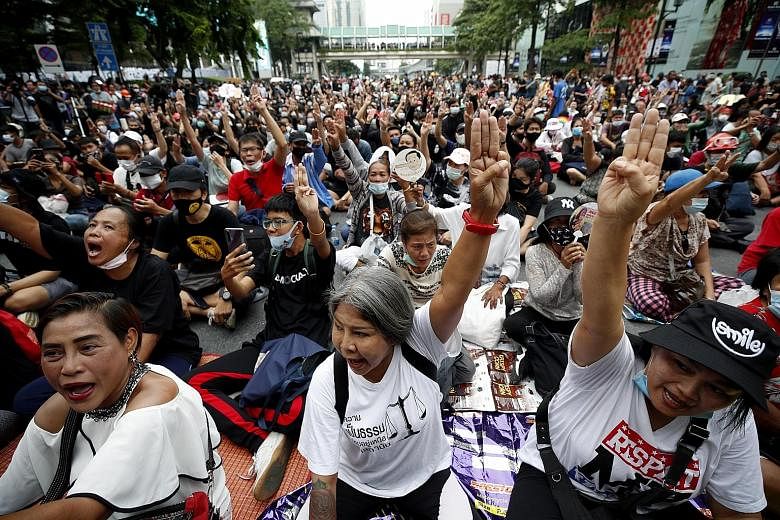 Activists flashing a three-finger salute at an anti-government Bangkok rally yesterday. They want the premier to resign, a rewrite of the 2017 Constitution and the authorities to "stop harassing" political opponents. PHOTO: EPA-EFE