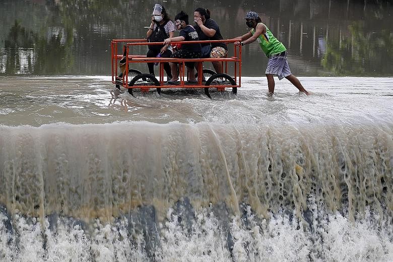 Villagers crossing an overflowing dam yesterday at the border between Cavite province and Las Pinas city, in the Philippines. Tropical cyclone wind alerts were issued for several provinces in the Bicol and Calabarzon regions with the storm Molave exp