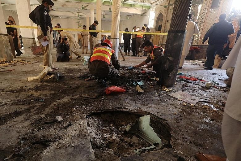 Investigators and workers searching for body parts at the site of a bomb blast at a religious school in Peshawar, north-western Pakistan, yesterday. A local hospital spokesman said seven bodies and 70 wounded people were taken to the medical facility