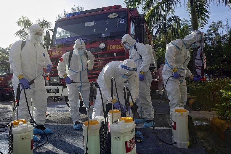 Firemen preparing to sanitise a building in Shah Alam, outside Kuala Lumpur, yesterday. Malaysia's third wave of coronavirus outbreaks has taken its toll on front-line workers, with up to 10,000 police personnel under quarantine and more than 200 pol