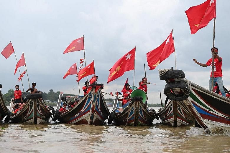 Supporters of the National League for Democracy party riding on wooden boats along Yangon river during an election campaign rally on the outskirts of Yangon yesterday, ahead of next week's elections. The party is widely expected to win the election -