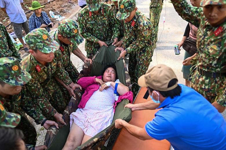 Above: Workers clearing debris following a landslide in central Vietnam's Quang Nam province. Right: Soldiers moving an injured woman onto a stretcher after she was rescued from a landslide in Tra Leng commune in Quang Nam yesterday.