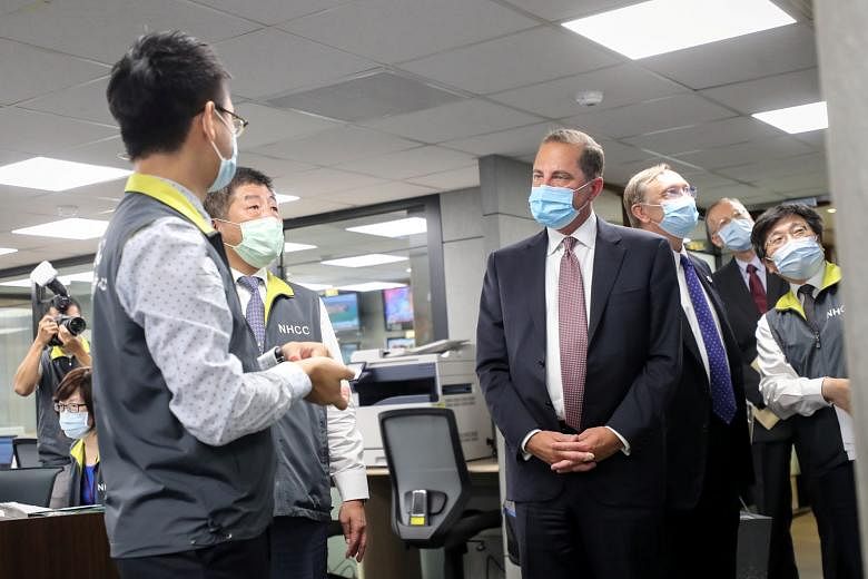 Above: Visitors to Xingtian Temple in Taipei getting their temperature checked. Except for wearing face masks and washing hands more often, life has returned to normal in Taiwan. Left: US Secretary of Health and Human Services Alex Azar wearing a fac