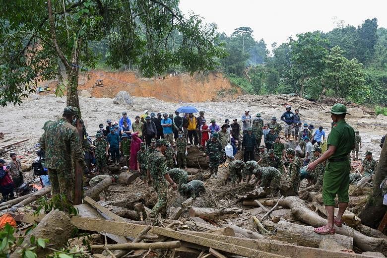 Left: A boy being comforted by a relative after losing his father in the landslides in Nam Tra My district in Vietnam's Quang Nam province yesterday. Below: Rescuers and residents searching yesterday for those missing after three landslides struck Na