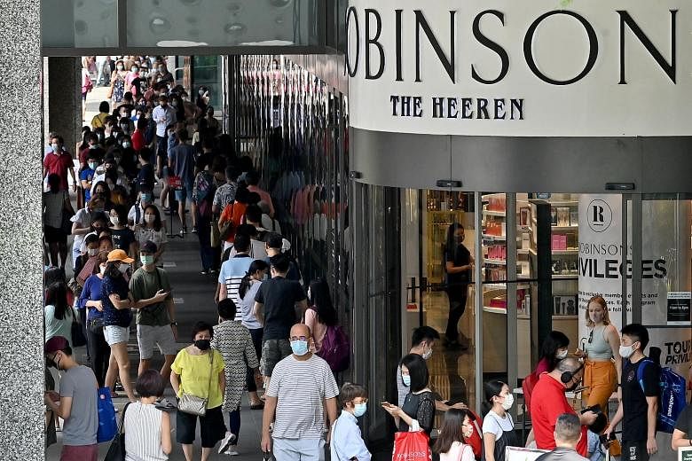 Left: The queue at Robinsons' store at The Heeren in Orchard Road yesterday began forming before the store opened at 11am. It stretched past the Apple store down the road and snaked around the empty space in front of the mall several times. Top: Shop