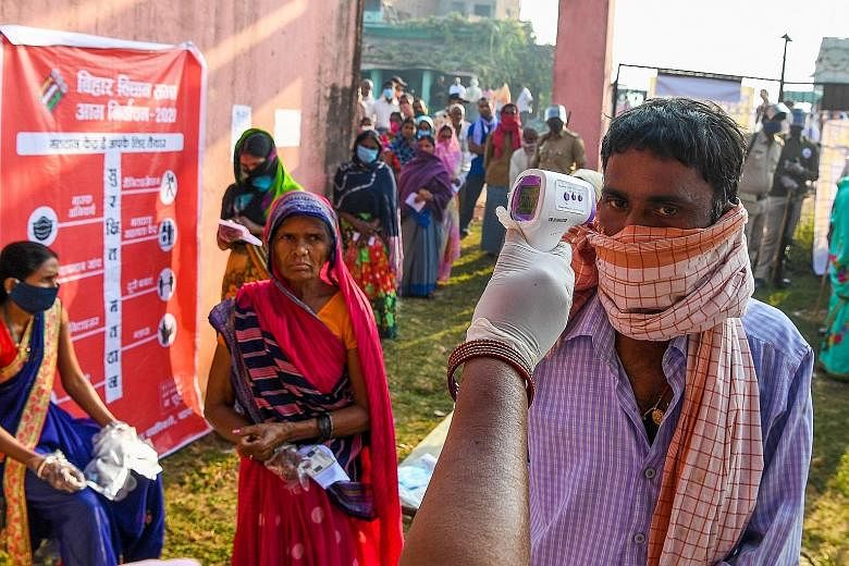 An election official checking the temperature of a voter at a polling station for the Bihar state assembly elections, in the city of Patna last week. The Bharatiya Janata Party's pledge of free vaccines as Bihar heads to the polls has got the opposit