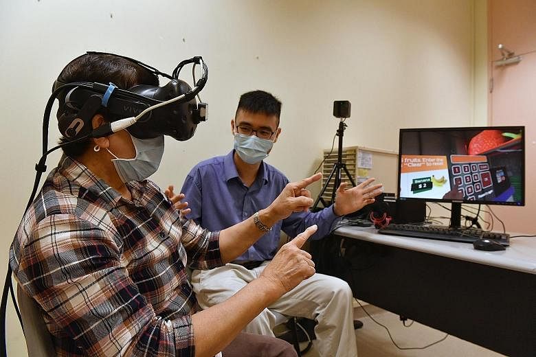 (Left) Retired nurse Seah Ai Choo trying out the virtual-reality system to assess her cognitive function while being guided by medical student Lim Jie En at SingHealth Outram Polyclinic on Sept 28. (Left) In one scenario, users have to follow the ins