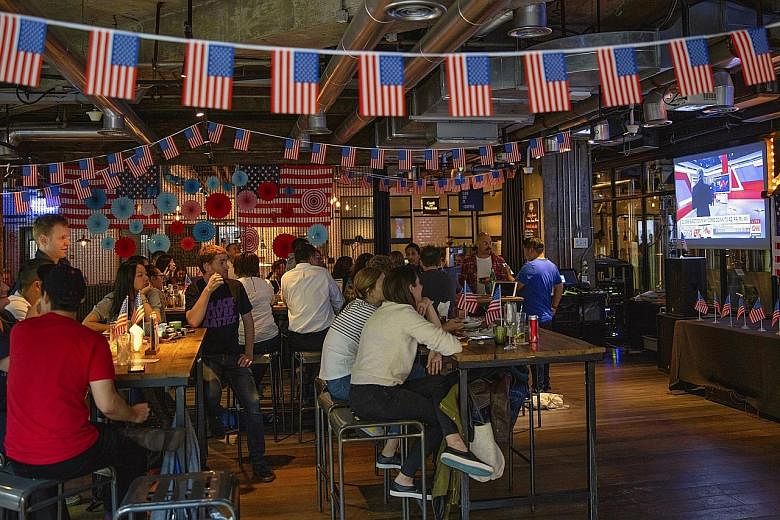 People tracking the US election results on television in a restaurant in Shanghai, China, yesterday. Crowds packed pubs and cafes for watch parties across Asia as the outcome of the presidential race remained uncertain.