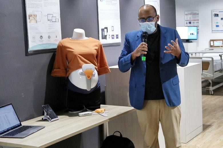 Above: Biorithm chief executive and co-founder Amrish Nair showing off the firm's foetal monitor. Right: A demonstration on how to wear one of the pieces of clothing designed by local start-up Will & Well for post-stroke patients.