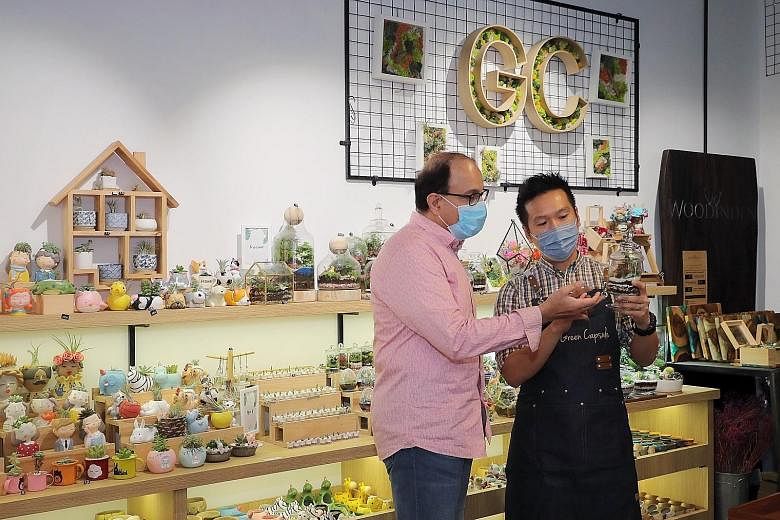 Communications and Information Minister S. Iswaran looking at a terrarium with The Green Capsule owner Ricky Lim at his store in Funan mall yesterday. Having adopted e-commerce and inventory management solutions, Mr Lim now wants to use data analytic