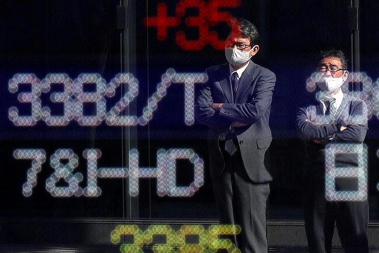People outside a brokerage in Tokyo yesterday. Japan's Nikkei 225 ended up nearly 0.3 per cent. The positive tone in Asian equities came after Pfizer said its Covid-19 vaccine was over 90 per cent effective in preventing infection, marking the first 