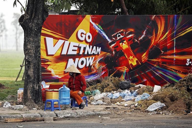 A street vendor sitting in front of a poster promoting the Vietnamese Grand Prix at the construction site of the Hanoi Street Circuit in March. The race will not be on the calendar for next year, while F1 did not give a reason for its omission.