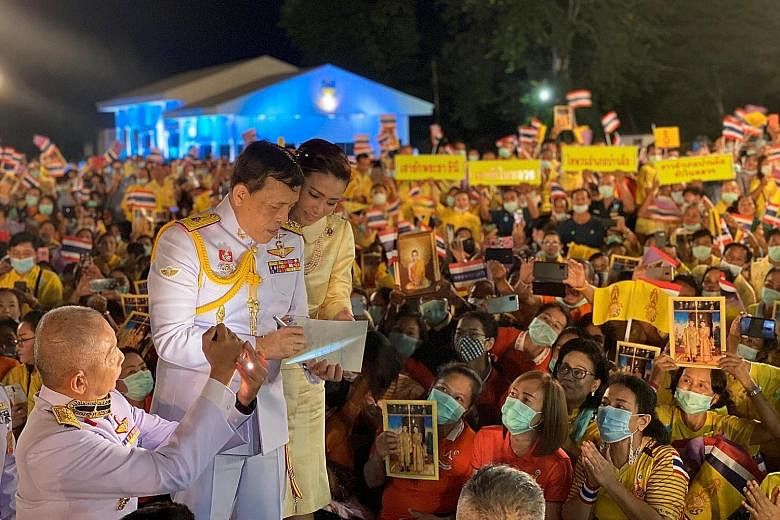King Maha Vajiralongkorn, seen here with Queen Suthida, writing a message as the couple greeted royalists in Thailand's Udon Thani province on Tuesday. On a picture of himself and the Queen that was brought by one well-wisher, the King wrote: "Love t