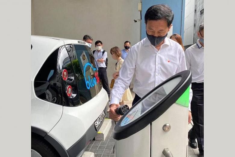 Transport Minister Ong Ye Kung beside a BlueSG electric vehicle (EV). He said the authorities are reviewing the plan to increase the number of EV-charging points to see if commercial parties could be roped in.