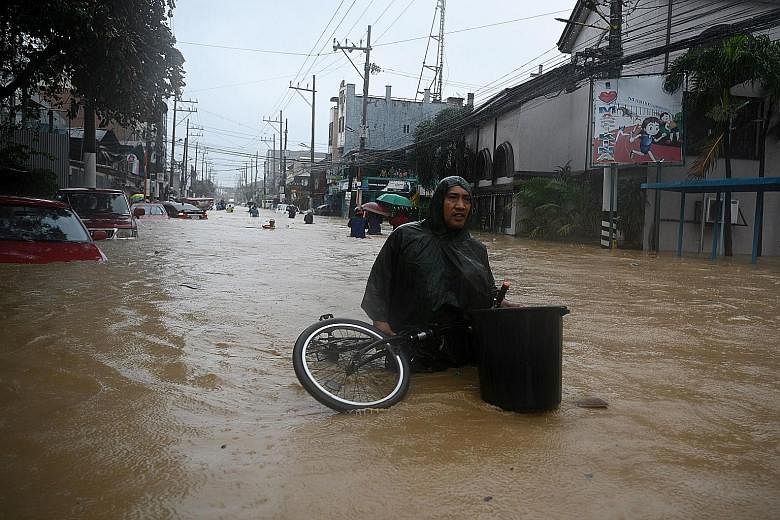 A resident with his belongings making his way through a flooded street to get to a shelter, after Typhoon Vamco hammered Marikina city yesterday. PHOTO: AGENCE FRANCE-PRESSE