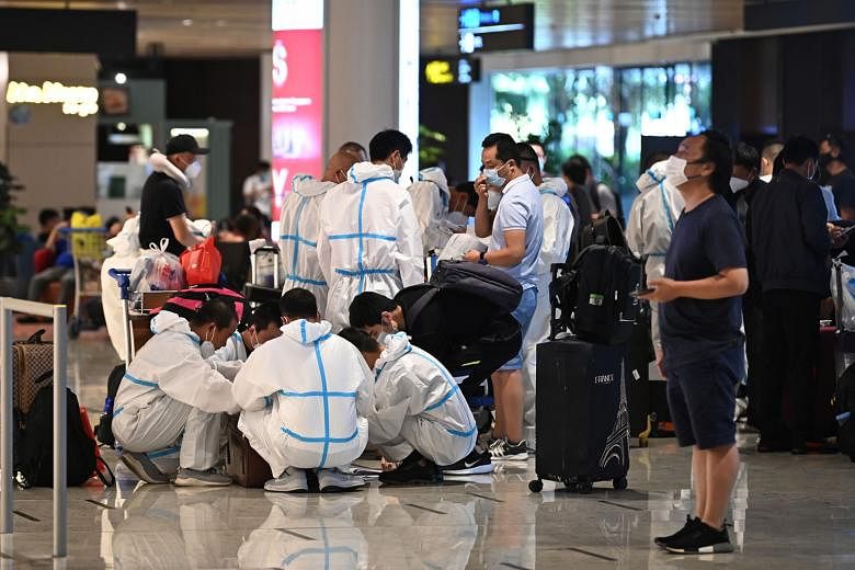Passengers wearing isolation gowns on arrival at Changi Airport. The 11 new imported cases, of which two were symptomatic, tested positive while serving their stay-home notice. There were no new community cases and none from workers' dormitories. Wit
