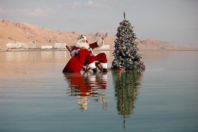Santa Claus striking a pose for the cameras after sticking a Christmas tree on a salt formation in the Dead Sea yesterday.