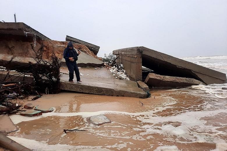A man standing on the remains of a bridge destroyed by Typhoon Vamco in Vietnam yesterday. Vamco is the latest in a series of storms to have pummelled Vietnam over the past six weeks.