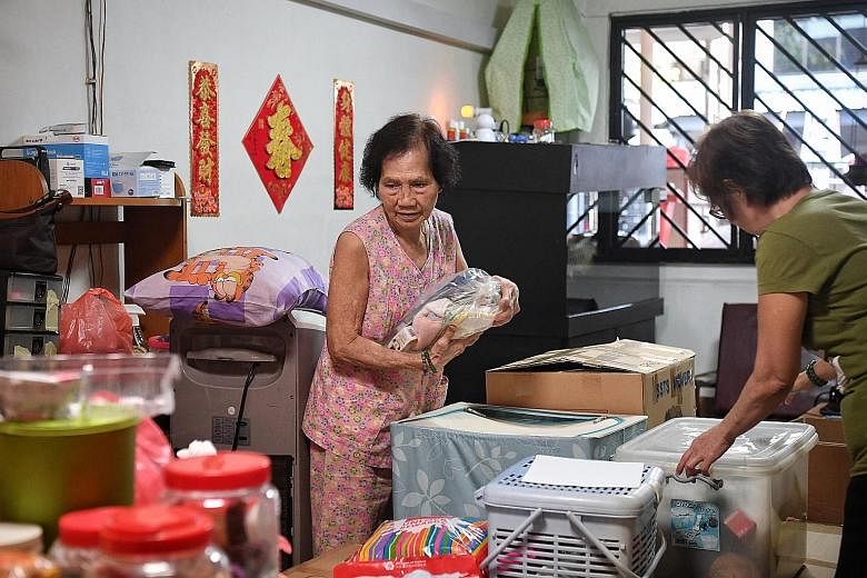 Madam Yeo Ai (far left) packing up her possessions with the help of her daughter, Ms Joyce Koh, in the Geylang Lorong 3 house where she has lived for close to six decades. She is one of 37 home owners who will have to vacate their homes by Dec 31, wh