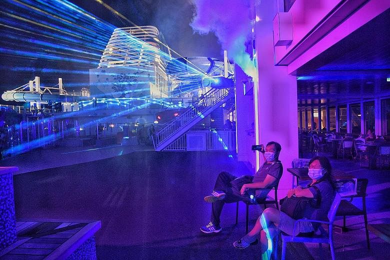 Guests, unfazed by pandemic protocols such as having to take a Covid-19 swab test (right) before boarding the cruise liner, lap up what World Dream has to offer, from the nightly laser shows (above) to more than 35 international dining (left) and bar