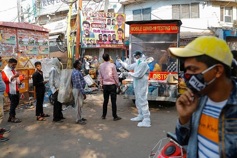 A healthcare worker in personal protective equipment collecting a swab sample from a man while others await their turn at a wholesale market in the old quarter of Delhi, India, yesterday. The city recorded 3,797 new cases on Monday, the highest numbe