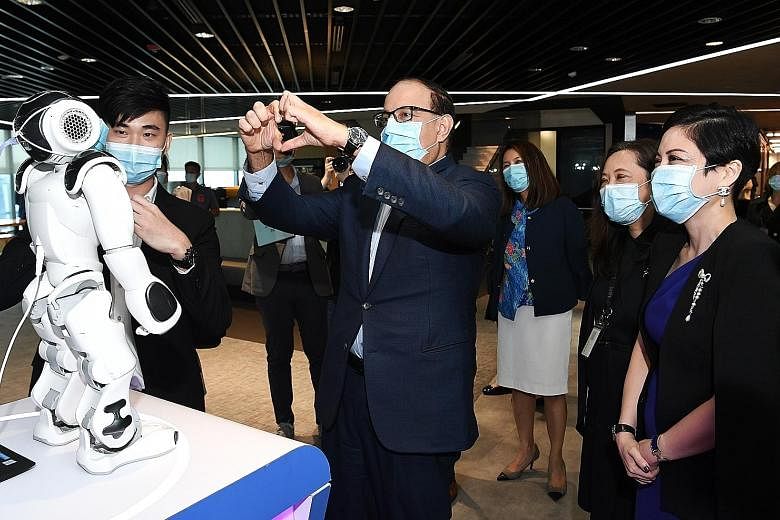 Communications and Information Minister S Iswaran making a gesture to Nao, a humanoid robot which can recognise hand gestures, during his visit to IBM yesterday. He was at the tech firm to witness the signing of the memorandum of intent between IBM a