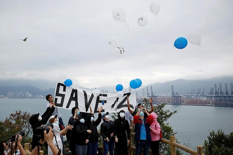 The protesters releasing balloons with the names of the 12 detainees yesterday on Hong Kong's Kat O island, overlooking the area where the Chinese prison is located. The 12 were caught on Aug 23 trying to flee the city by boat. PHOTO: REUTERS