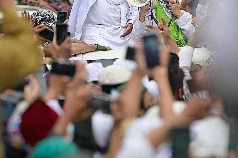 Cleric Rizieq Shihab greeting supporters in Jakarta on Nov 10 after returning to Indonesia from Saudi Arabia. Thousands turned out to greet him despite health protocols limiting gatherings to five people.