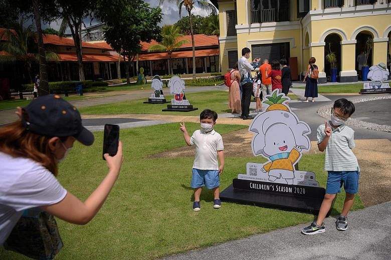 Ms Jermaine Chua, 33, snapping a picture of her sons - four-year-old Tate and seven-year-old Ian - as they posed with a standee of Ai on the front lawn of the Malay Heritage Centre last Friday. The mascot created by artist Peter Draw is at the centre