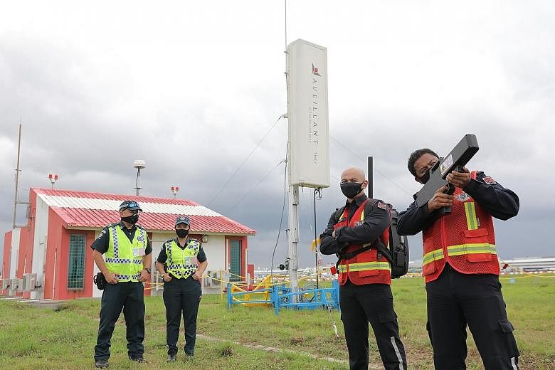 Ground enforcement officers (far left) and mobile disruption team officers next to the counter-unmanned aircraft system radar (in white), which is used to detect drones, at Changi Airport yesterday. The officer on the right is holding a radio frequen