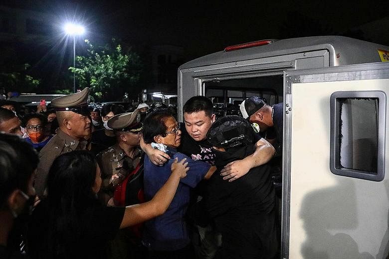 Pro-democracy activist Parit Chiwarak being helped out of a police van as it arrived at a police station in Bangkok on Oct 30, after he was released from jail over protest-related offences.