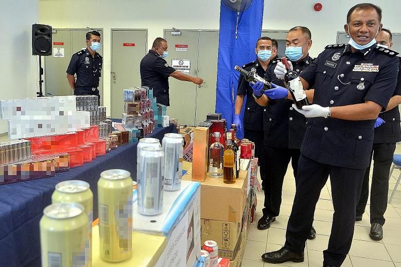 Shah Alam Assistant Commissioner of Police Baharudin Mat Taib displaying to the media a haul of liquor and cigarettes sold without proper permits at business premises. PHOTO: BERNAMA