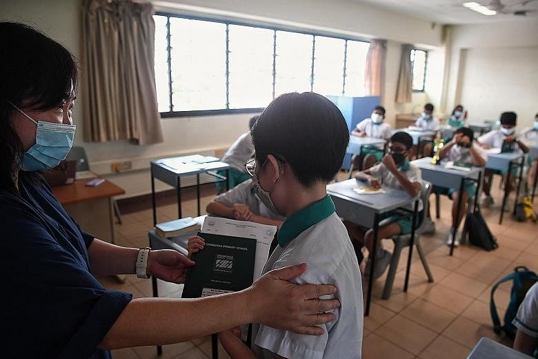 Accompanying persons waiting in the hall of Zhonghua Primary School. Due to the young age of PSLE pupils, a parent or guardian was allowed to accompany the child or ward to school to collect the results. ST PHOTOS: KUA CHEE SIONG Pupils collecting th