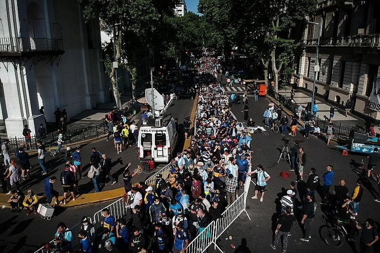 Thousands waiting yesterday to visit the funeral chapel of football legend Diego Maradona installed at the Casa Rosada in Buenos Aires. Above: Fans filing past the Argentinian football legend's casket. Right: Distraught fans embracing in the streets.