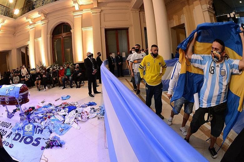 Thousands waiting yesterday to visit the funeral chapel of football legend Diego Maradona installed at the Casa Rosada in Buenos Aires. Above: Fans filing past the Argentinian football legend's casket. Right: Distraught fans embracing in the streets.