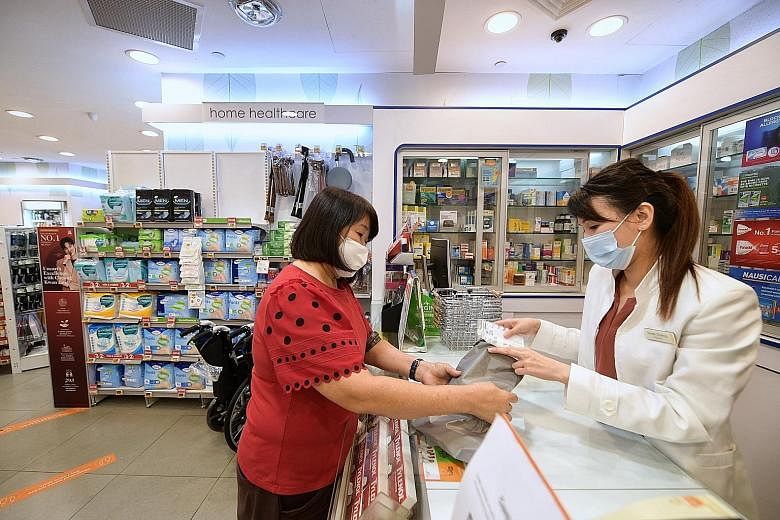Retiree Yoo Bee Eng, 64, a caregiver to a patient of Singapore General Hospital, collecting the patient's medication from a Guardian store yesterday. ST PHOTO: NG SOR LUAN