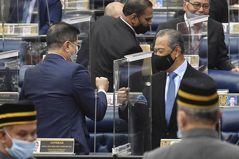 Malaysian Prime Minister Muhyiddin Yassin (right) exchanging a fist bump with International Trade and Industry Minister Azmin Ali after the parliamentary session in Kuala Lumpur yesterday. The PM is barely holding on to a majority, with just the need