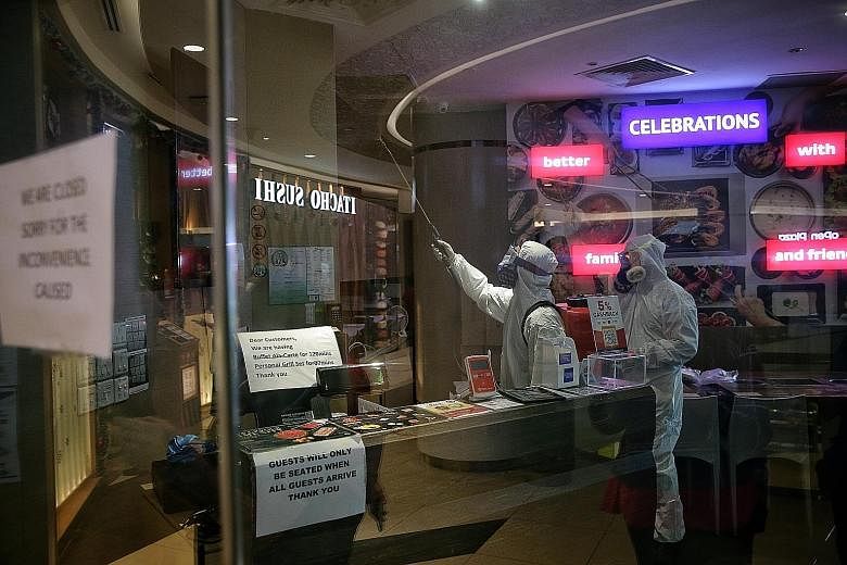 Staff from Clean Solutions, a professional cleaning company, disinfecting the interior of the Seoul Garden restaurant in Tampines Mall yesterday. Mr Garry Lam, Seoul Garden Group's general manager, said the family of 13 did not come to the restaurant